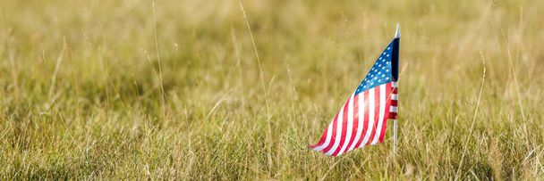 草の畑にアメリカの国旗が掲揚されている。パノラマ - 写真・画像