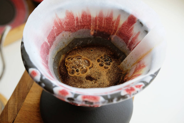 Свіжообсмажена кава, що цвіте в керамічному ремеслі, керамічна глиняна крапельниця v60. Концепція спеціальної кави
 - Фото, зображення