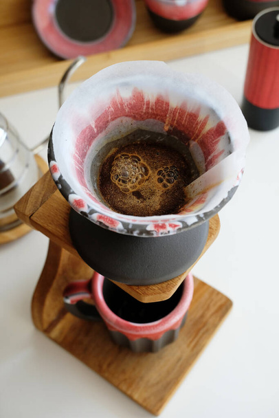 Kaffeezubereitung in Keramik-Ton-Set: Tropfer v60 und Becher auf Holzständer. Kaffeespezialitätenkonzept. Ansicht von oben - Foto, Bild