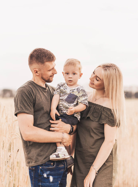 Beautiful family parents and a young son in a wheat field. Mom, Dad and Baby Together. Happy family, parents hugs their little son - Φωτογραφία, εικόνα