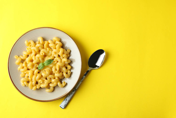 Plate with macaroni and cheese on yellow background - Foto, afbeelding