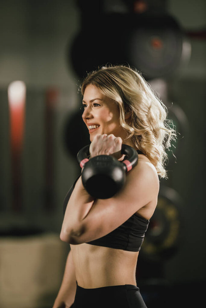 A young muscular woman working out with kettlebell at the gym. - 写真・画像