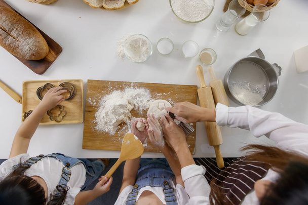 Hands of woman adult and little girls mixing flour on board to make bakery, top view angle. - Foto, Bild