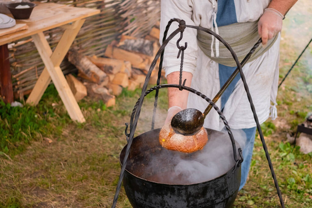 Preparación de sopa en la olla colgante sobre fuego abierto - concepto de camping - Foto, Imagen