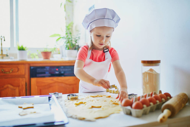 Adorable preschooler girl making cookies. Child helping to cook food in the kitchen. Cooking for little kids - Photo, image
