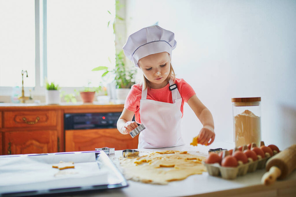 Adorable preschooler girl making cookies. Child helping to cook food in the kitchen. Cooking for little kids - Foto, Imagem