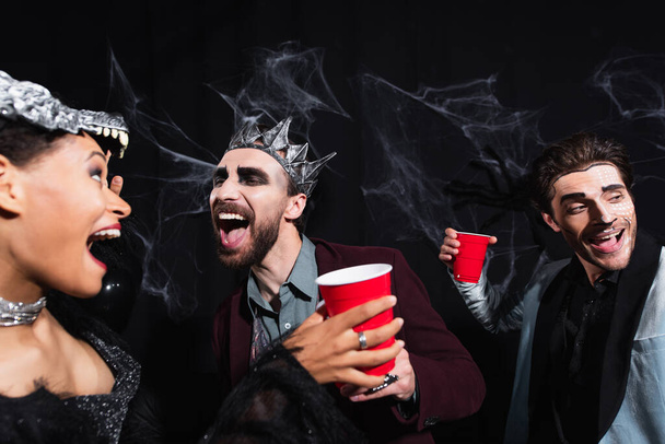 izgatott multietnikus barátok halloween jelmezek tánc közben party a fekete - Fotó, kép