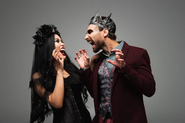 spooky interrazziale coppia in vampiri halloween costumi spaventare ogni altri isolato su grigio - Foto, immagini