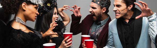 багатоетнічні друзі з пластиковими чашками лякають один одного під час вечірки на Хелловін ізольовані на сірому, банер
 - Фото, зображення