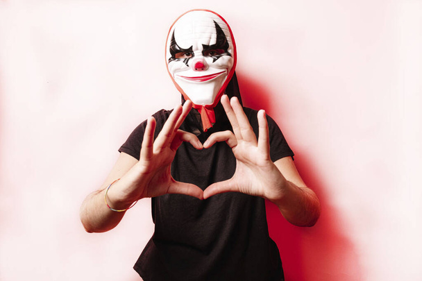 Woman in a halloween mask making a heart with her hands, on colored background. Halloween concept. - Foto, Imagem