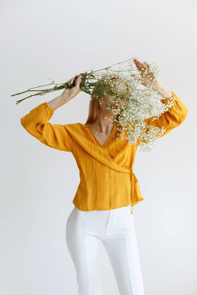 блогер з квітами покриває обличчя на монохроматичному фоні
 - Фото, зображення
