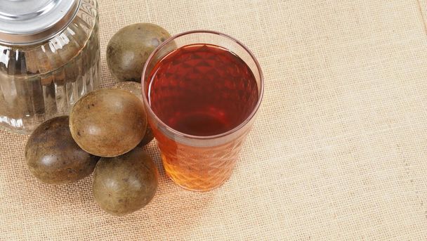 Monk meyvesi veya Luo Han Guo. Sağlıklı tatlandırıcı için kurutulmuş meyve. Doğal bitkisel ilaç ve cam şişe arka planı. Sağlık ve şeker yedeği için keşiş meyvesi içeceği.  - Fotoğraf, Görsel