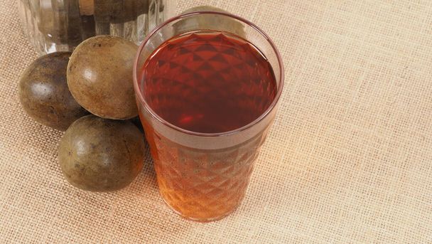 Monk fruit or Luo Han Guo. Dried fruits for healthy sweetener drink. Natural herbal remedy and glass bottle background. Monk fruit drink for who concern health and sugar substitute.  - Photo, Image
