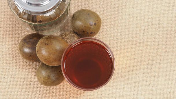 Monk fruit or Luo Han Guo. Dried fruits for healthy sweetener drink. Natural herbal remedy and glass bottle background. Monk fruit drink for who concern health and sugar substitute.  - Photo, Image