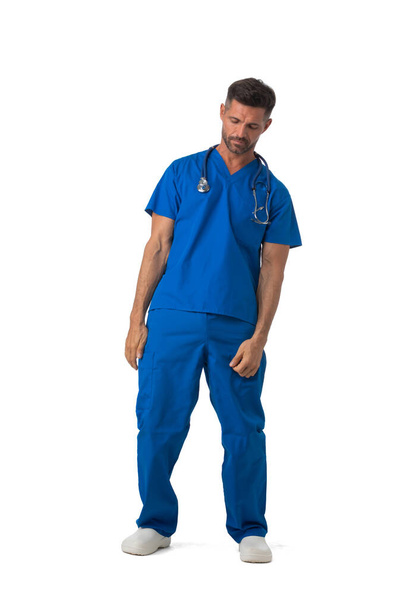 Tired sleepy doctor standing in medical clothing with eyes closed full length portrait isolated on white background - Photo, Image