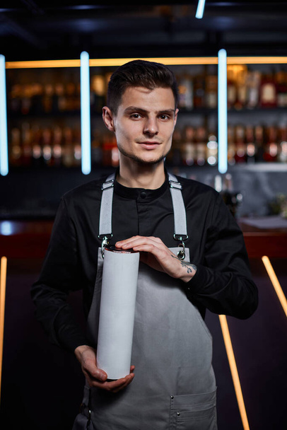 Handsome barman in apron standing at the bar counter - Valokuva, kuva