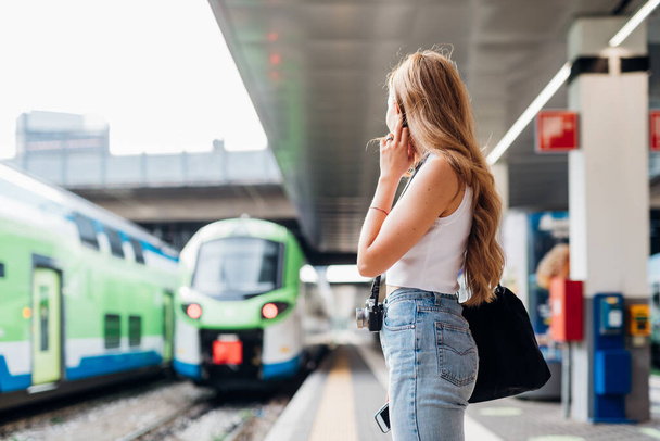 Jovem caucasiana espera trem na plataforma ferroviária para chegada e partida - Foto, Imagem