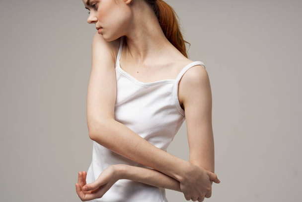 woman in white t-shirt holding on to the elbow health problems joint treatment studio treatment - Fotografie, Obrázek