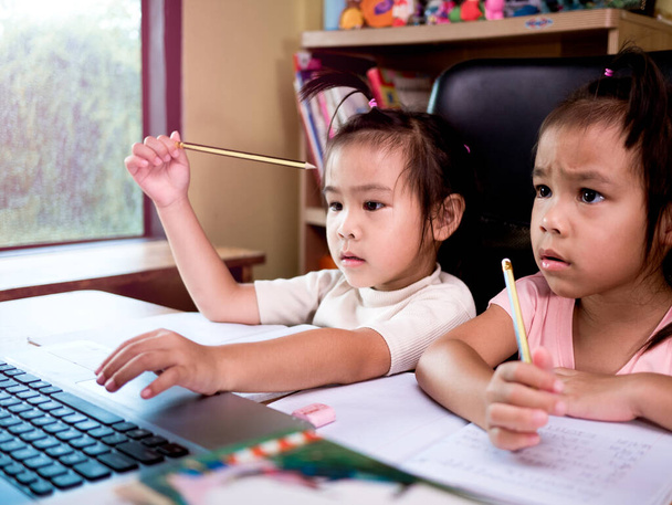 Evdeki çevrimiçi dersi sırasında ödev matematiği okuyan iki küçük kız. Coronavirus salgını sırasında sosyal mesafeler. Çevrimiçi eğitim kavramı ya da evde öğrenim. - Fotoğraf, Görsel