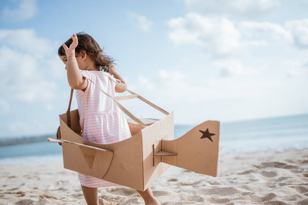 kid run at the beach play with toy airplane made of cardboard - Foto, imagen