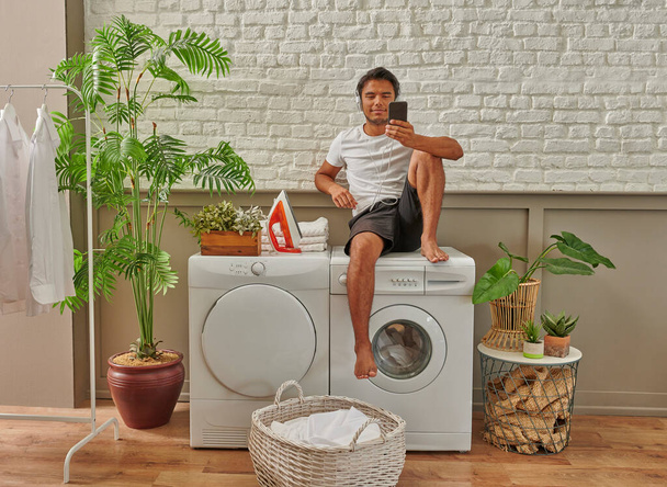 Мужчина чистит одежду стиральная машина вид сверху, прачечная. - Фото, изображение