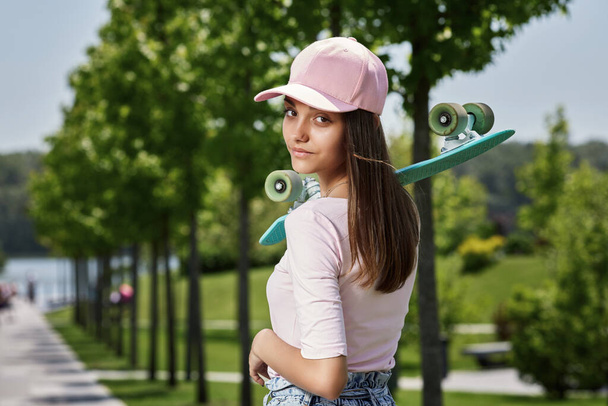 young skateboarder girl with skateboard standing outdoors - Foto, imagen
