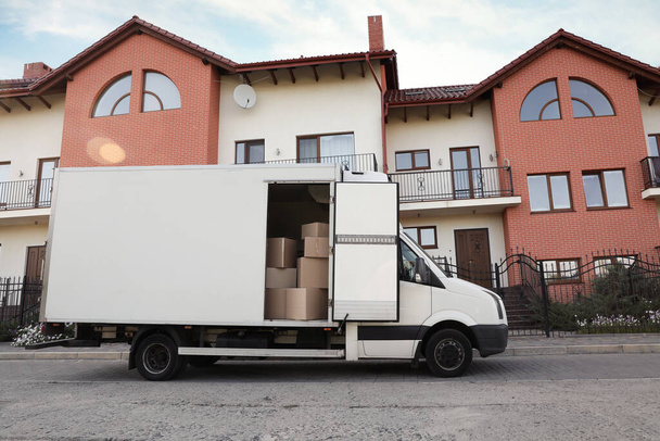 Van full of moving boxes near new house - Фото, зображення