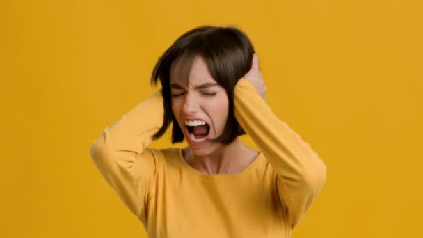 Τρελή γυναίκα που καλύπτει αυτιά με τα χέρια φωνάζοντας Όχι, κίτρινο φόντο - Πλάνα, βίντεο