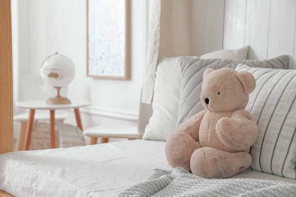 Comfortable bed with cushions and toy in room. Interior design - Фото, зображення