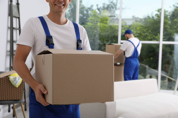 Moving service employees with cardboard boxes in room, closeup - 写真・画像