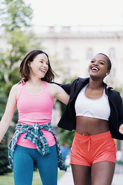 Deux filles multiethniques marchant pour une séance d'exercice, communiquant en plein air. - Photo, image