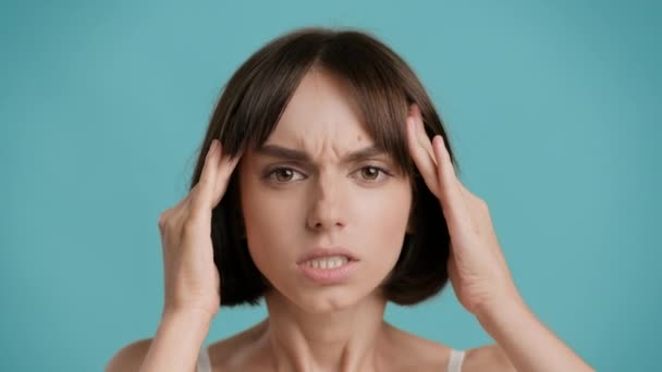 Žena s bolestivou bolestí hlavy trpí masáže spánků, modré pozadí - Záběry, video