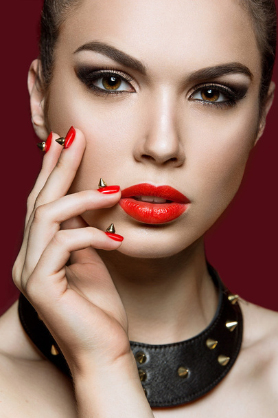 Hermosa mujer con maquillaje de noche y uñas rojas con espinas
. - Foto, imagen