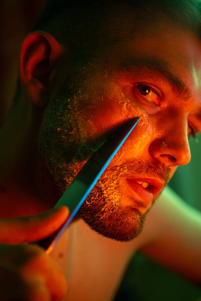 ανδρικό πορτραίτο με μαχαίρι σε νέον φως - Φωτογραφία, εικόνα