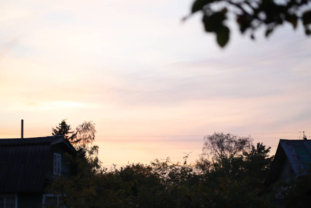 田舎でしか見られない景色村家の屋根からの美しい夕日 - 写真・画像