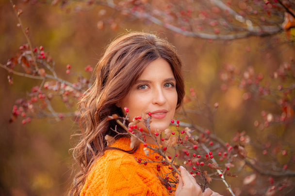 egy fiatal nő egy őszi parkban narancssárga pulóverben. - Fotó, kép
