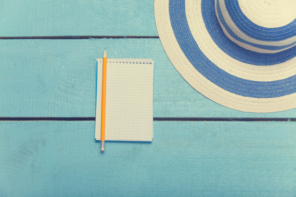 notebook with pencil and hat on blue wooden table - 写真・画像