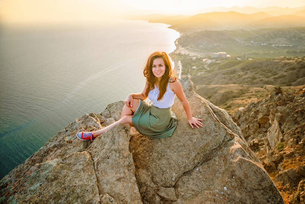 Photo panoramique d'une femme heureuse aux mains ouvertes qui a conquis le sommet d'une falaise avec une belle vue sur la mer et le paysage urbain. Le concept de voyage et de liberté. - Photo, image