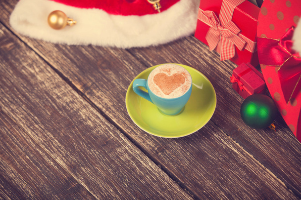 Чашка кофе в форме сердца с рождественскими подарками
. - Фото, изображение
