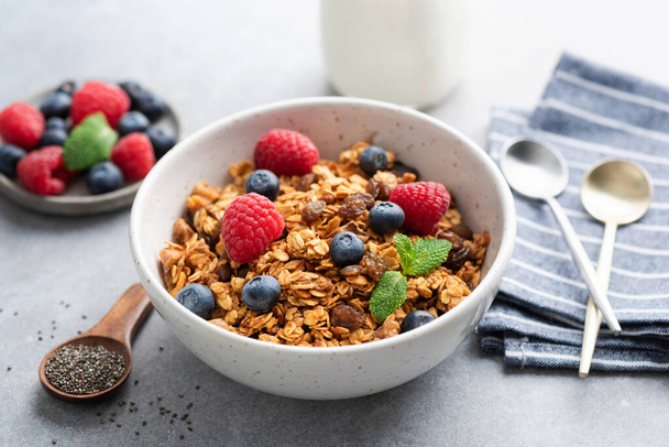 Bowl of homemade oat granola with berries on concrete table background. Healthy breakfast cereals, healthy diet food - Fotoğraf, Görsel