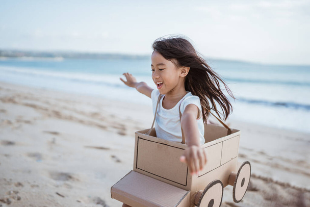 Дочь играет с картонным самолетом на пляже - Фото, изображение