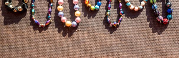 Haufenweise bunte bunte Schmuckperlen auf dunklem Hintergrund. Verschiedene Edelsteine Perlenkette. Juwelenkette moderne Mode Muster oder Textur. Raum für Text. Hochwertiges Foto - Foto, Bild
