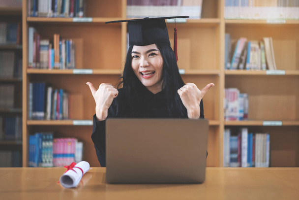 Young Asian female university graduate with degree celebrates virtual graduation through a video call - Foto, imagen