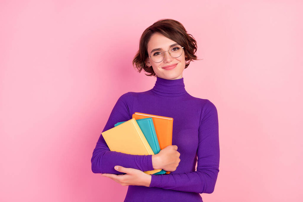 Foto von smart Brünette junge Dame halten Bücher tragen Brille violetten Pullover isoliert auf rosa Hintergrund - Foto, Bild