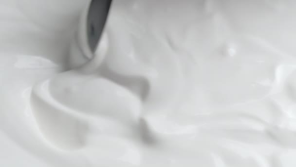 Κοντινό πλάνο γυρίσματα του μπολ με κρέμα γάλακτος και βουτηγμένο κουτάλι - Πλάνα, βίντεο