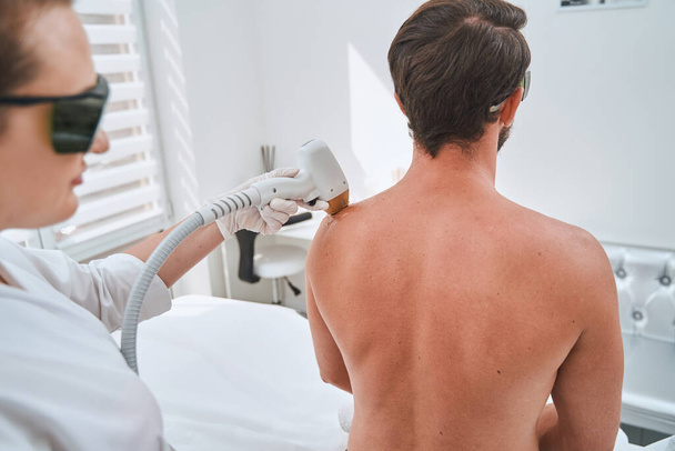Спа-клиент проходит процедуру лазерной эпиляции плеча - Фото, изображение