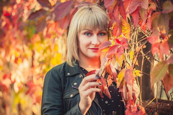 Portret of Young woman with bob haircut in a black leather jacket is standing in an abandoned greenhouse in autumn. - Foto, Bild