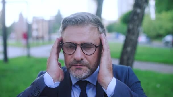 Upset bearded man in business suit suffering terrible migraine, touching head - Materiał filmowy, wideo