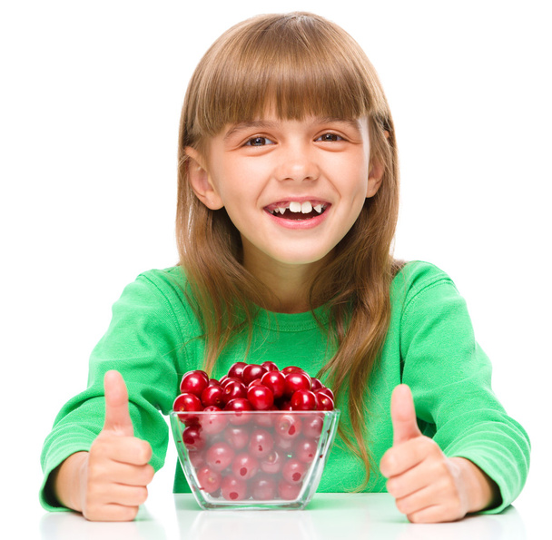 Cute girl is eating cherries showing thumb up sigh - Foto, Imagen