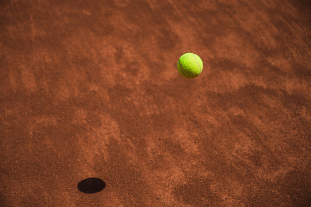 Yellow tennis ball in motion fluing under clay tennis court. Process of game. Sport. Lifestyle. - 写真・画像